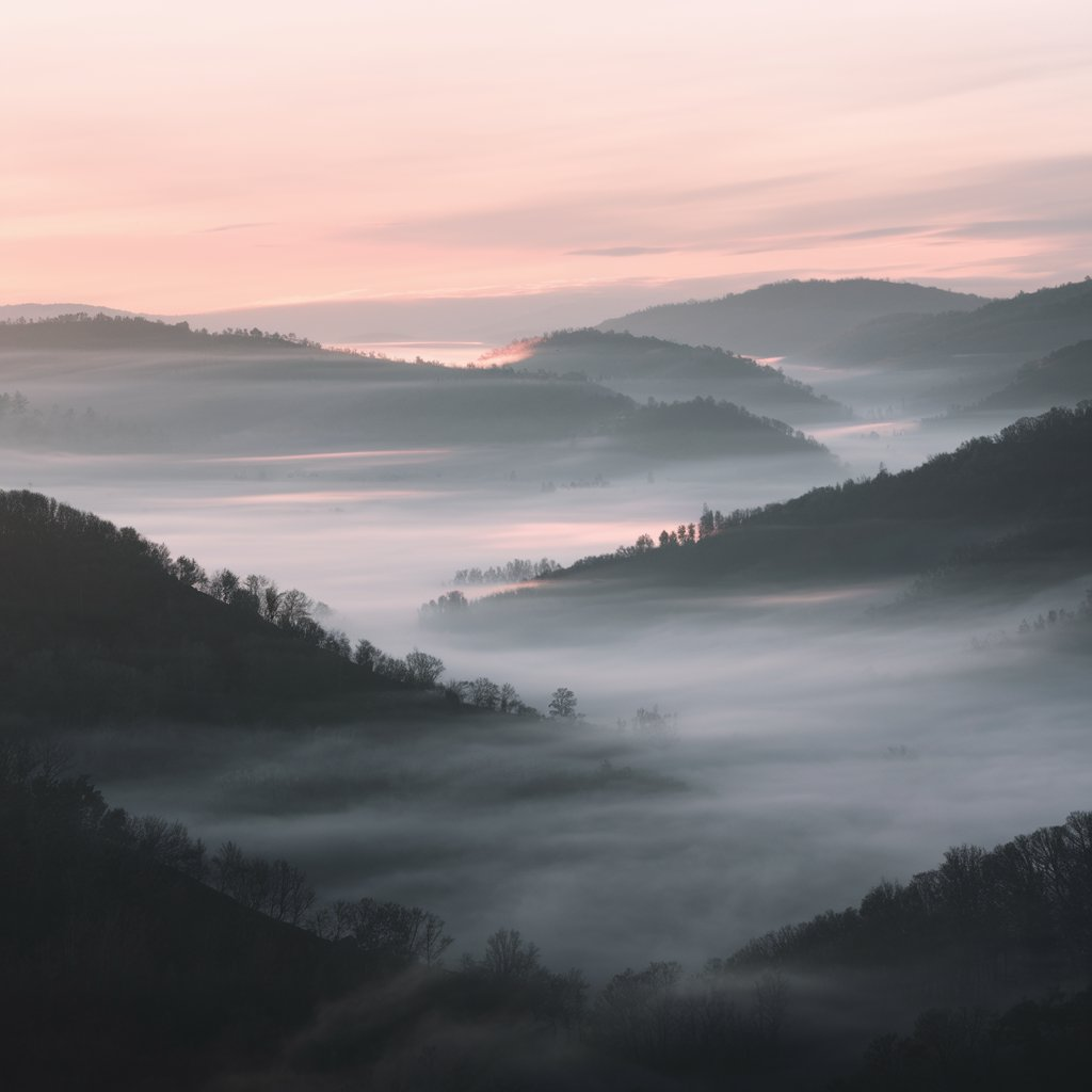 How to meditate A highly minimal landscape of rolling hills or mountains, covered in mist, with a soft sunrise or sunset glow, symbolizing quiet introspection.